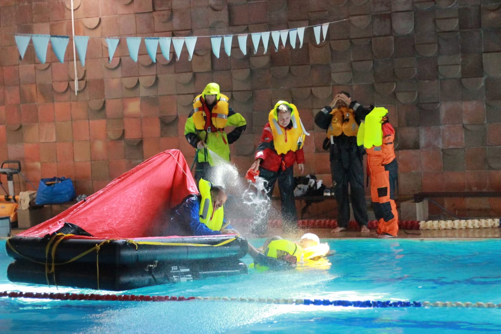 Students in inflated life jackets at the practical training with the liferaft in the pool
